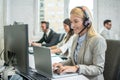 Portrait of blonde haired operator woman working on laptop in call center. Royalty Free Stock Photo