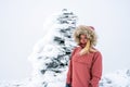 Portrait of blonde hiker girl with fur hooded jacket and backpack outdoors in the mountains