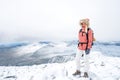 Portrait of blonde hiker girl with fur hooded jacket and backpack outdoors in the mountains