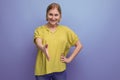 portrait of blonde middle aged woman in yellow t-shirt stretching out her hand for a handshake on studio background Royalty Free Stock Photo