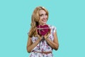 Portrait of blonde middleaged woman holding a heart shape gift box in both hands. Royalty Free Stock Photo