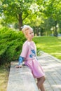 Portrait of a blonde in pink attire in a park outdoors.