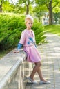 Portrait of a blonde in pink attire in a park outdoors.