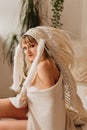 portrait of a blonde woman in a blanket in an Indian headdress of white feathers Royalty Free Stock Photo