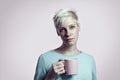 Portrait of blonde woman with cup of water, short hair background bright background Royalty Free Stock Photo