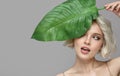 Portrait of blonde woman and green leaf. Organic cosmetics concept.