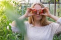 Portrait of blonde woman harvesting red ripe organic tomatoes in greenhouse and having fun. Healthy homegrown food Royalty Free Stock Photo