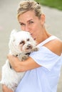 Portrait of blonde woman holding a cute little white dog Royalty Free Stock Photo