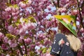 woman with a Japanese hat next to a blooming cherry tree