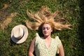 Portrait of blonde woman with long hair, young and beautiful farmer, lying on fresh green grass. Next to her a straw hat. The girl Royalty Free Stock Photo