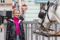 portrait of a blonde woman 35-40 years old, looking at a horse-drawn carriage in a European city. Royalty Free Stock Photo