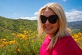 Portrait of a blonde young adult woman in a field of poppies and mixed wildflowers during the California super bloom Royalty Free Stock Photo