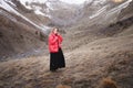 Portrait of a blonde young woman with bright blue eyes in a black dress and a red down jacket walks in the fall in the Royalty Free Stock Photo