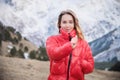 Portrait of a blonde young woman with bright blue eyes in a black dress and a red down jacket walks in the fall in the Royalty Free Stock Photo