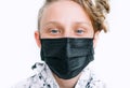 Portrait of blue-eyed teen boy using a black facial mask during a COVID-19 world pandemic looking at the camera. Self-protection Royalty Free Stock Photo