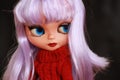 Portrait of Blythe doll with purple hair, blue eyes and red sweater