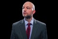 Portrait of a bold unshaven businessman in a grey suit ted tie and blue shirt on a black background Royalty Free Stock Photo