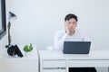 Portrait of bored Asian young handsome businessman wear white shirt working with laptop at office. Unmotivated employee