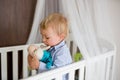 Portrait of bored baby standing in crib. Baby boy stand alone in crib. Sad little baby Royalty Free Stock Photo