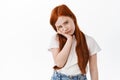 Portrait of bored cute red head little girl with freckles, face palm and stare at something boring, sulking upset