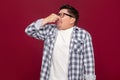 Portrait of bored handsome middle aged business man in casual checkered shirt and eyeglasses standing and blocking his nose