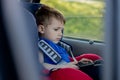 Portrait of a bored little boy sitting in a car seat. Safety of transportation of children Royalty Free Stock Photo