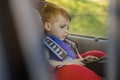 Portrait of a bored little boy sitting in a car seat. Safety of transportation of children Royalty Free Stock Photo