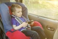 Portrait of a bored little boy sitting in a car seat. Safety of transportation of children Royalty Free Stock Photo
