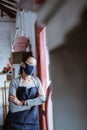 portrait boring woman florist wearing apron and face mask lean on door