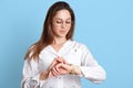 Portrait of bossy successful businesswoman in glasses, isolated over light blue background. Slender brown haired model looks at