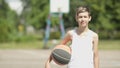 Portrait of a boy with a ball on a street basketball field, oversaturation of light