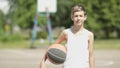 Portrait of a boy with a ball on a street basketball field, oversaturation of light