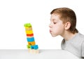 Portrait of a boy blowing on falling house made of wooden blocks Royalty Free Stock Photo