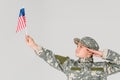 portrait of boy in camouflage clothing saluting and looking at american flagpole in hand Royalty Free Stock Photo