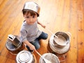 Portrait, boy child playing drums on pots on a floor, curious and enjoying music. Face, top view and kid with pans for Royalty Free Stock Photo