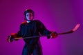 Half-length portrait of boy, child in protective uniform for hockey isolated over purple studio background in neon light Royalty Free Stock Photo