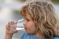 Portrait of boy drinking glass of water. Kid drinking water outdoor. Thirsty child. Royalty Free Stock Photo