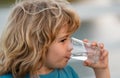 Portrait of boy drinking glass of water. Kid drinking water outdoor. Thirsty child. Royalty Free Stock Photo