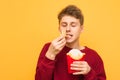 Portrait of a boy eating French fries with eyes closed on a yellow background. Young man and fast food. Copyspace Royalty Free Stock Photo