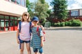 Portrait of a boy and a girl with backpacks on their backs in the school yard. Schoolchildren brother and sister go back