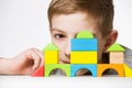 Portrait of a boy hiding behind house made of wooden blocks