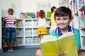 Portrait of boy holding book at school library Royalty Free Stock Photo