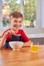 Portrait Of Boy At Home Eating Bowl Of Breakfast Cereal At Kitchen Counter