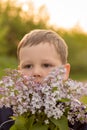 Portrait of a boy with lilac. bouquet of purple lilac in children`s hands. hands holding a purple lilac flowers bouquet in meadow Royalty Free Stock Photo