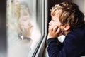 Portrait of boy looking out the window of his house bored, respecting quarantine for viruses in Europe