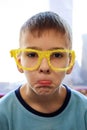 Portrait of a boy making faces in funny yellow glasses made on a 3d printer Royalty Free Stock Photo