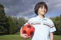 Portrait of boy in meadow with football looking away Royalty Free Stock Photo