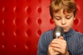 Portrait of boy with microphone against red wall Royalty Free Stock Photo