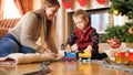 Portrait of boy with his mother playing on floor with toy train and railways. Child receiving presents and toys on New Royalty Free Stock Photo