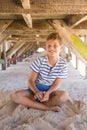 Portrait of boy playing with sand while sitting under hut Royalty Free Stock Photo